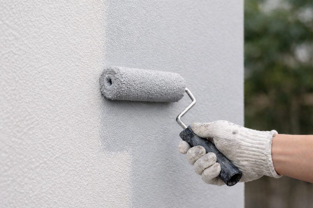 高耐久な無機塗料をローラーで外壁に均一に塗布している施工中の様子