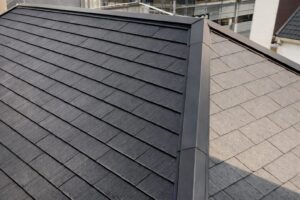 日本の戸建住宅に施工された切妻屋根の化粧スレート屋根。グレー系の落ち着いた色味と、スレート特有の控えめな艶感、整った重なりが分かる屋根のクローズアップ写真。