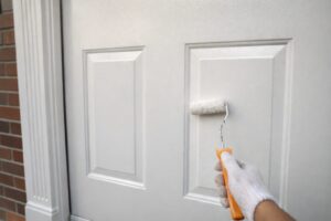 板橋区の住宅で木製玄関ドアをローラーで塗装している様子