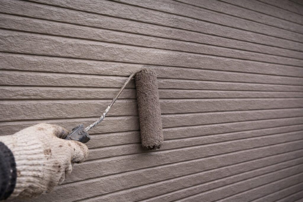 外壁塗装の中塗り工程でローラーを使い規定塗布量を意識して塗料を均一に塗布している様子