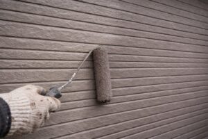 外壁塗装の中塗り工程でローラーを使い規定塗布量を意識して塗料を均一に塗布している様子