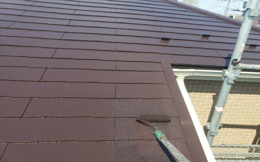 練馬区の集合住宅で屋根全体をローラーで上塗り塗装している施工中の様子