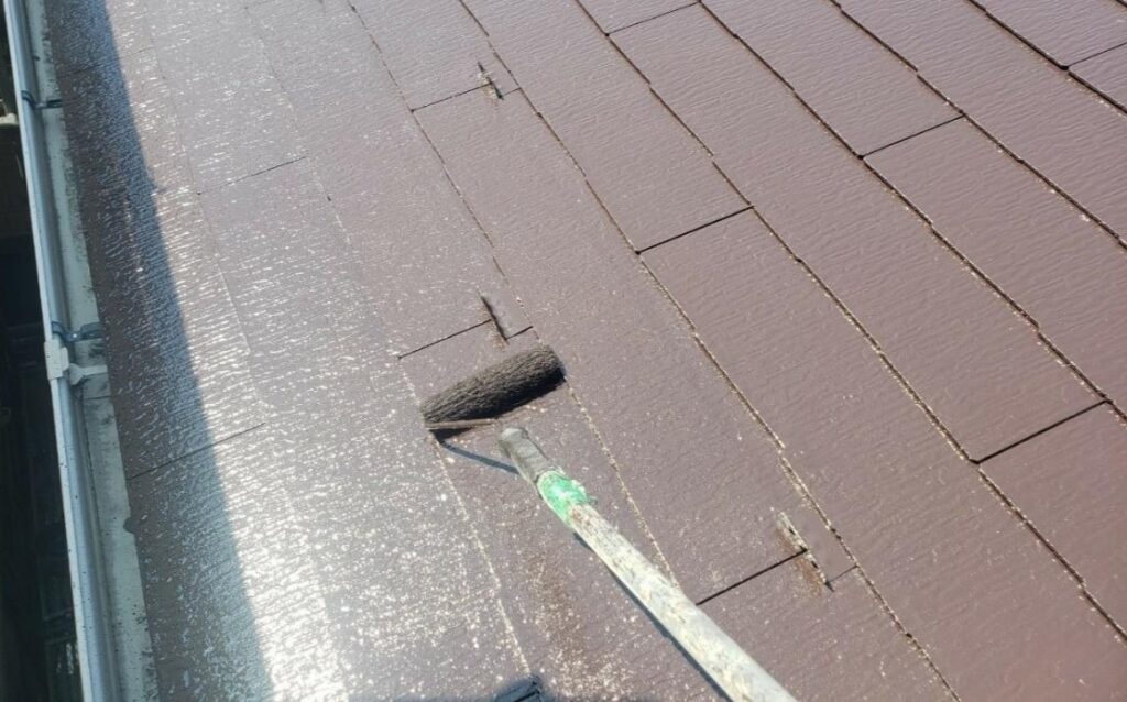 練馬区の集合住宅で屋根の上塗り塗装を行い、塗膜を均一に仕上げている様子