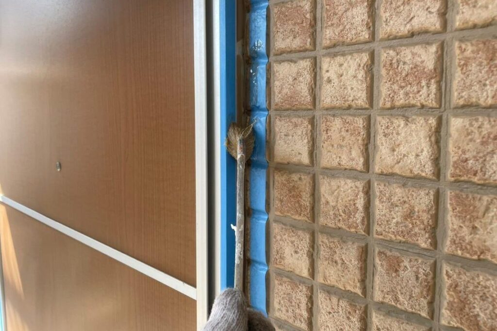 ドア周りの外壁とドア枠の取り合い部分にシーリング前のプライマーを塗布している様子