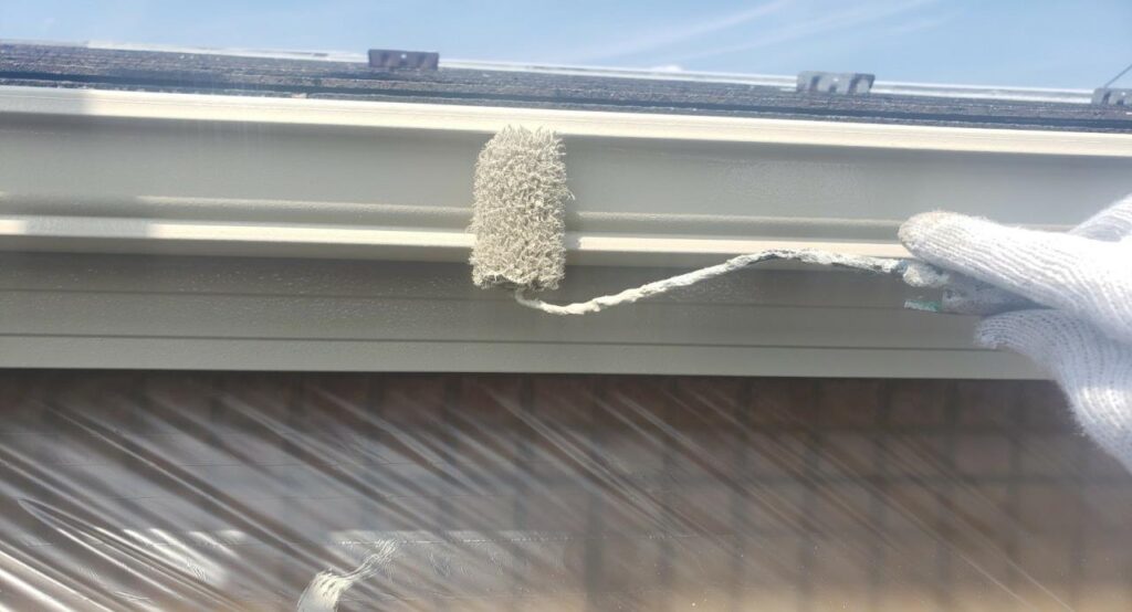 練馬区の集合住宅で、雨樋塗装工事の仕上げとして上塗り塗装を行っている作業中の様子