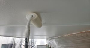 練馬区の集合住宅で、外壁塗装工事にあわせて軒天の上塗り塗装をローラーで施工している様子