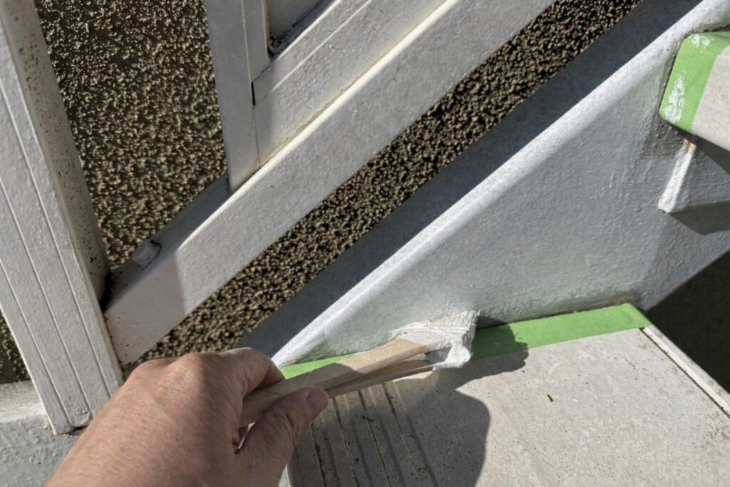 練馬区の集合住宅にある鉄骨階段ササラ取り合い部へ錆止め下塗り塗料を塗布している様子