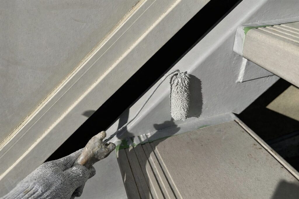 練馬区の集合住宅にある鉄骨階段ササラ取り合い部へ上塗り塗料を施工している様子