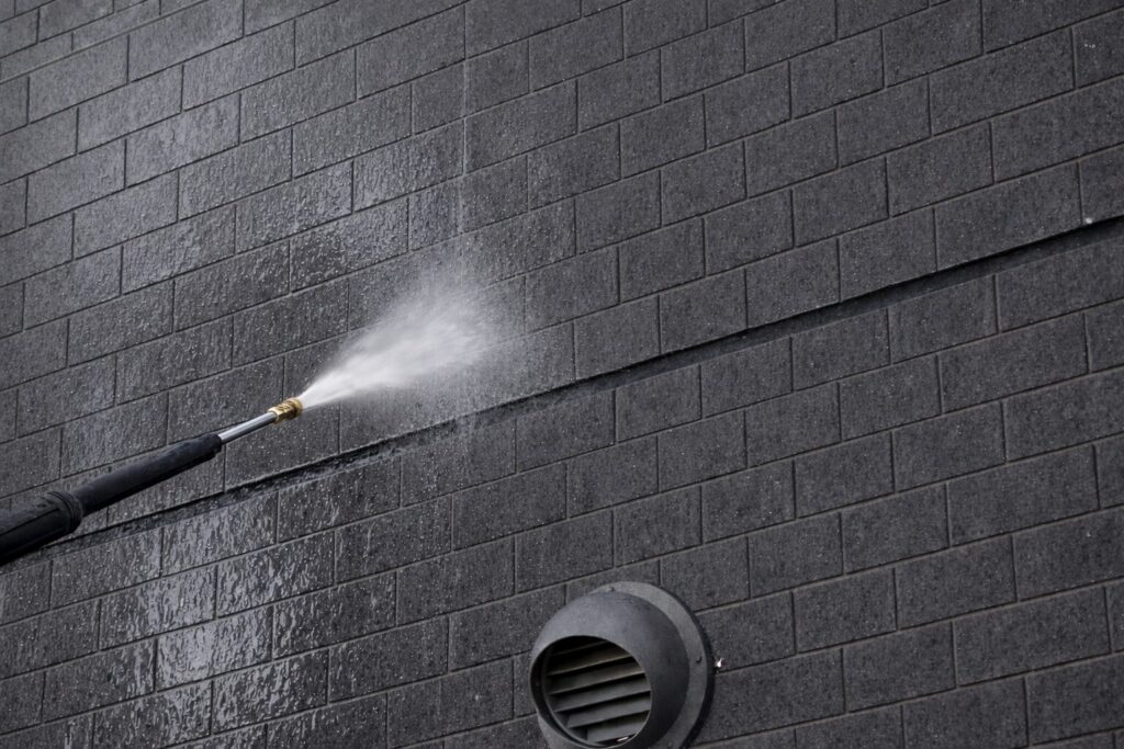 レンガ調外壁に発生したエフロレッセンスを高圧洗浄で除去している施工中の様子