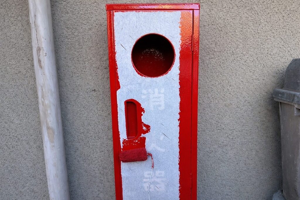 練馬区の集合住宅で消火器BOXの鉄部にローラーで中塗り塗装を行う作業