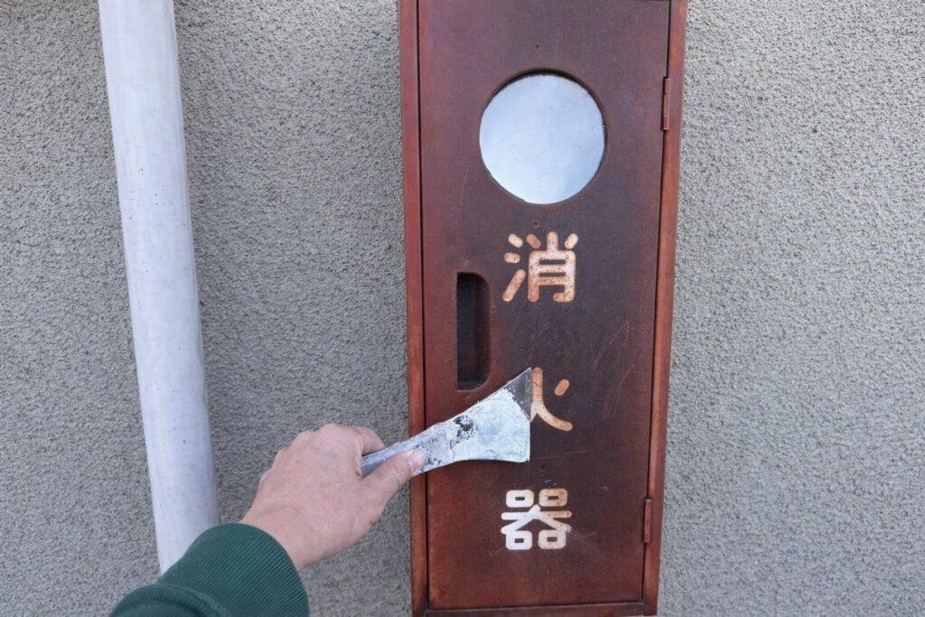 練馬区の集合住宅で消火器BOXの錆と劣化塗膜を皮スキで除去するケレン作業