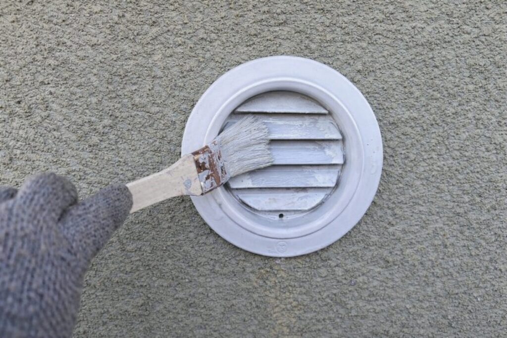 練馬区の集合住宅でガラリに刷毛で中塗り塗装を行う様子