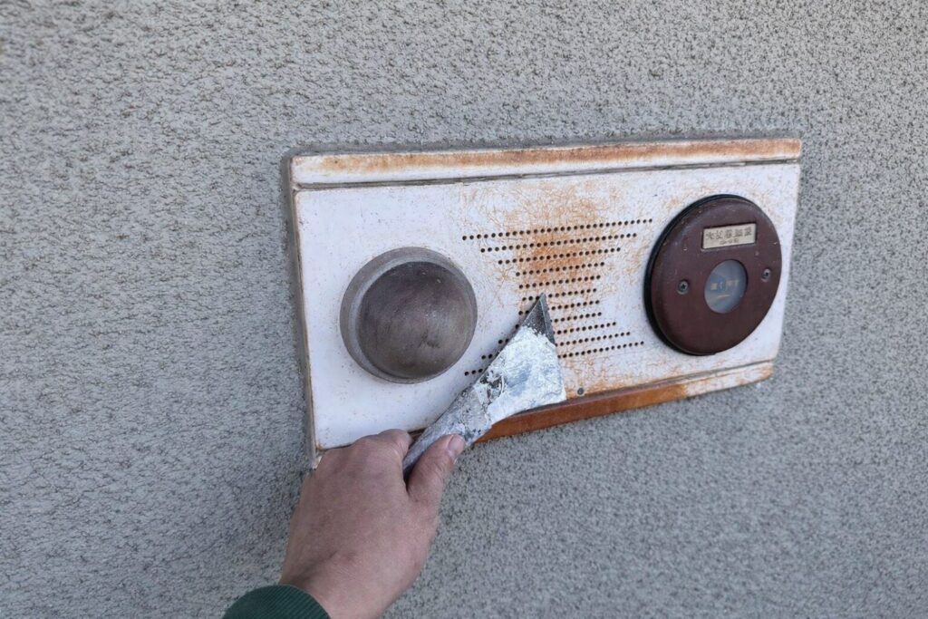 練馬区の集合住宅で火災報知器設備の鉄部に発生した錆をケレンして下地を整える作業