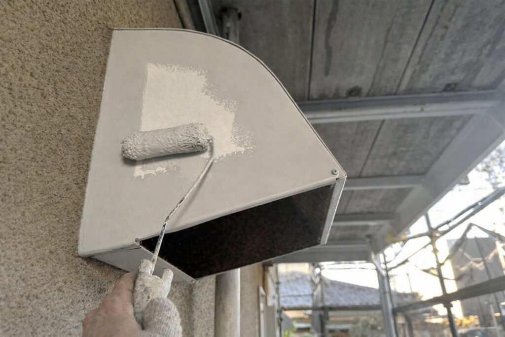 練馬区の集合住宅で換気フードにローラーで中塗り塗装を行う様子