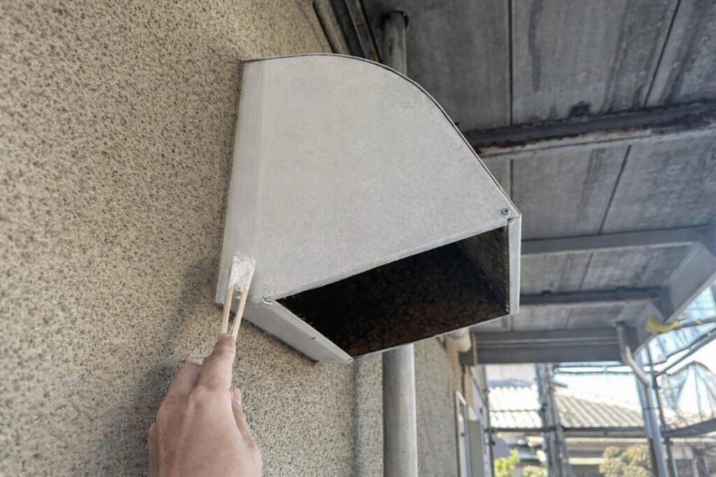 練馬区の集合住宅で換気フードに錆止め塗料を塗布している鉄部下塗り作業