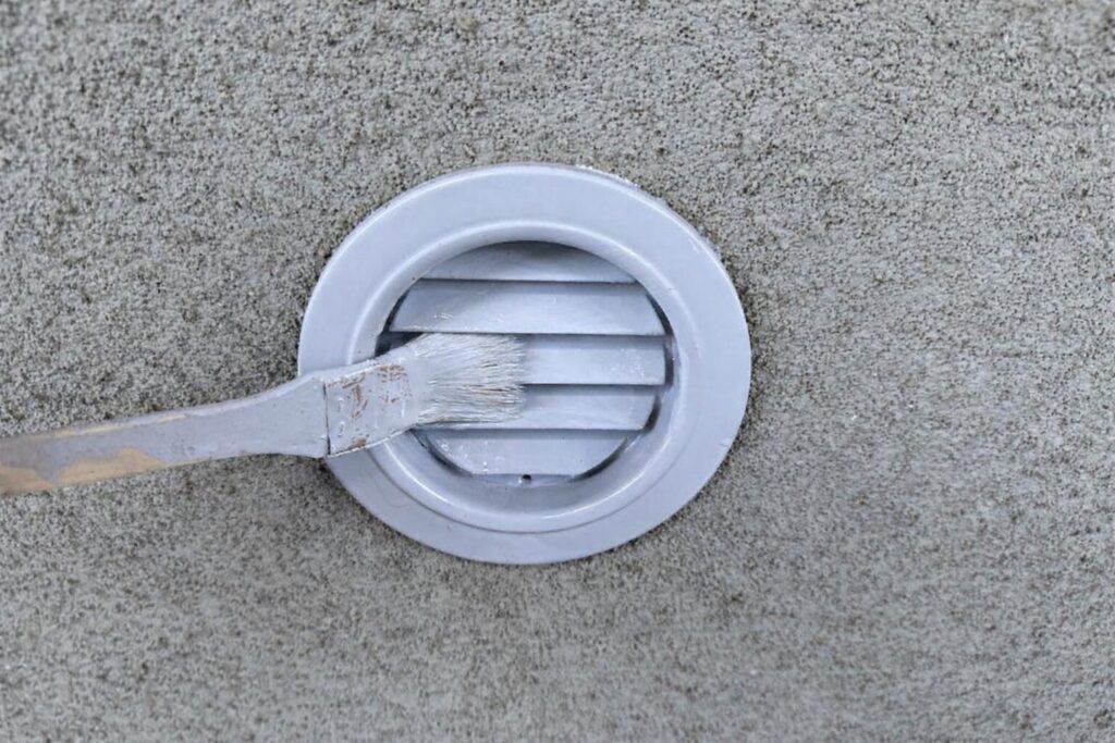 練馬区の集合住宅でガラリに刷毛で上塗り塗装を行う様子