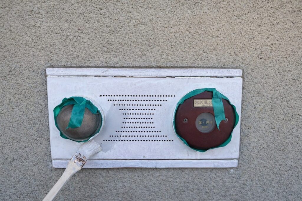 練馬区の集合住宅で火災報知器設備の鉄部に中塗り塗装を行う様子